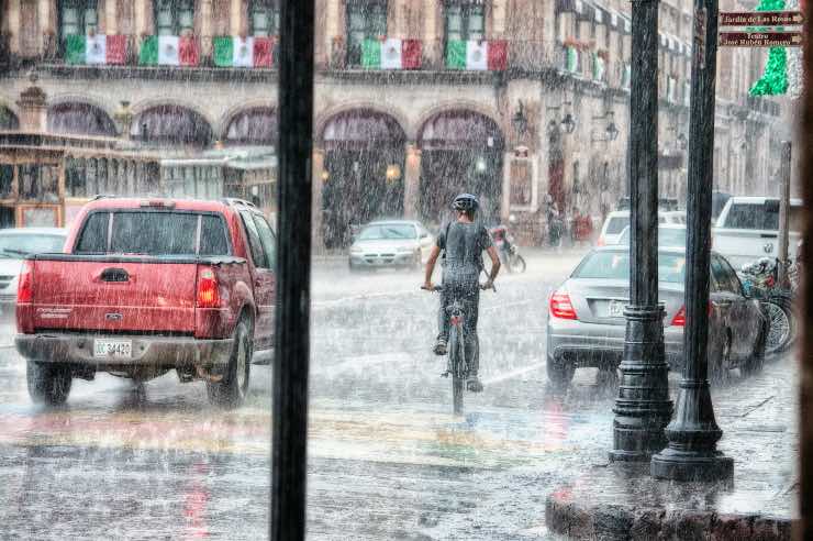 acquazzone in città tra macchine e bici 