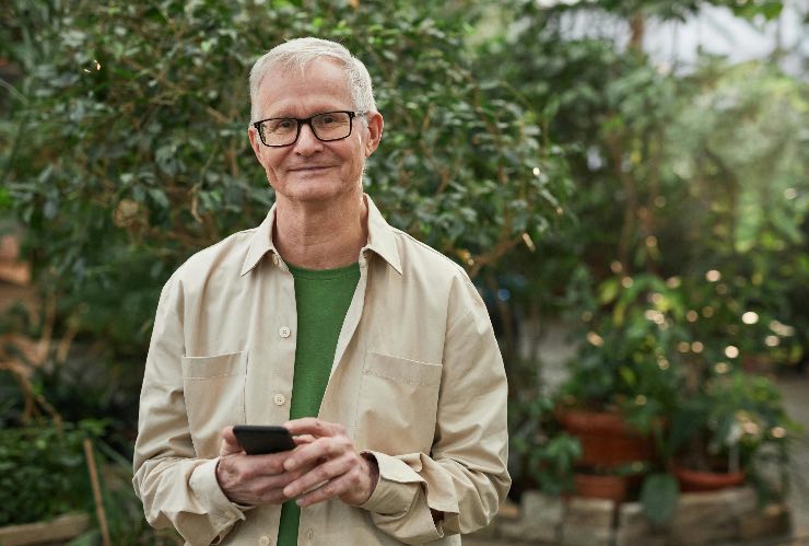uomo che sorride con in mano lo smartphone