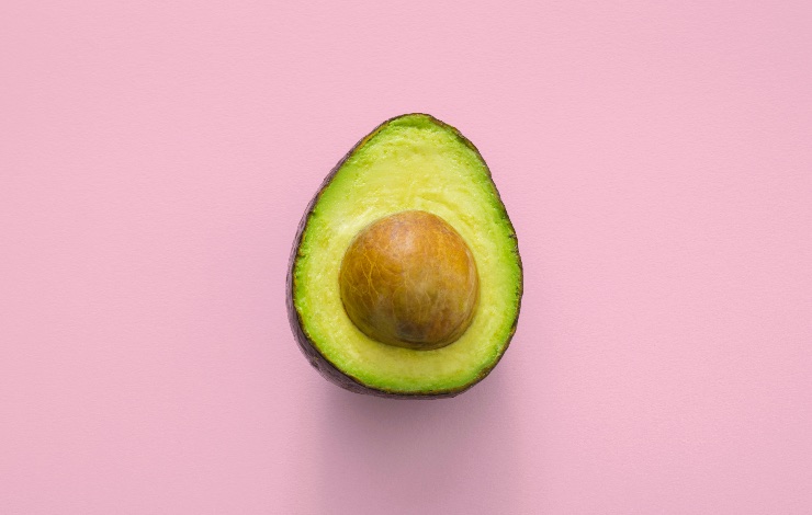 metà avocado su sfondo rosa 