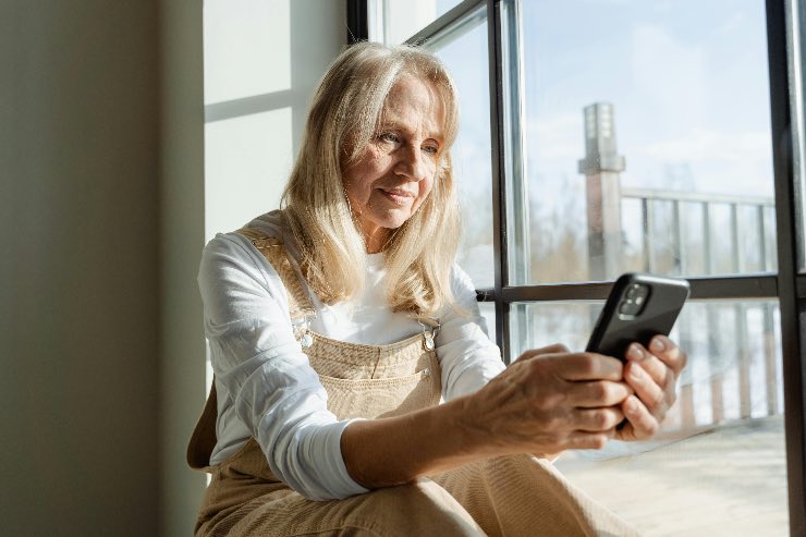 donna anziana che guarda lo smartphone a casa 