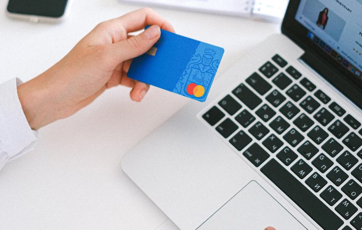 mano con carta di credito in mano e pc 