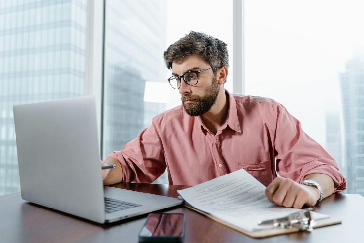 ragazzo che controlla documenti al pc in ufficio 