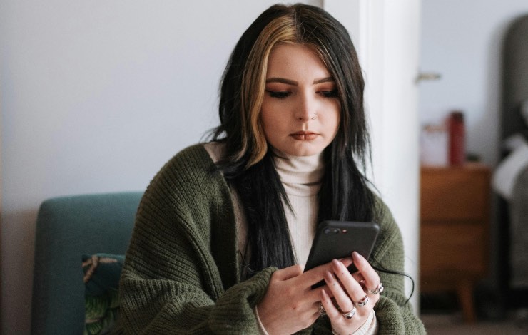 ragazza che guarda lo smartphone preoccupata 