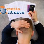 Uomo disperato di fronte a cartelle esattoriali e con in mano le carte di credito