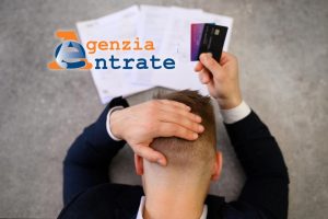 Uomo disperato di fronte a cartelle esattoriali e con in mano le carte di credito