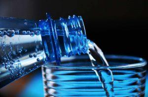 Primo piano bottiglia d'acqua che viene versata sul bicchiere