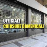 Serrande abbassate negozi e scritta: "ufficiale chiusure domenicali"