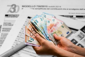 Documento dichiarazione dei redditi 730 sullo sfondo e mani con banconote euro in primo piano