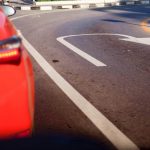 Auto rossa parte posteriore e strada con disegnato il simbolo dell'inversione di marcia