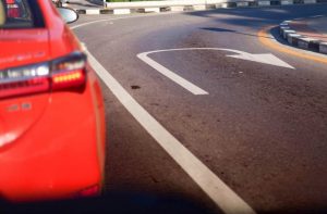 Auto rossa parte posteriore e strada con disegnato il simbolo dell'inversione di marcia
