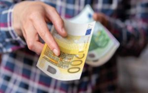Mano che porge banconote da 100 e 200€