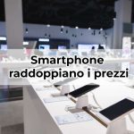 Negozio di elettronica con smartphone esposti e scritta "smartphone raddoppiano i prezzi"