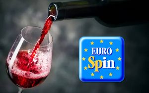 Bottiglia versata su calice di vino e logo Eurospin