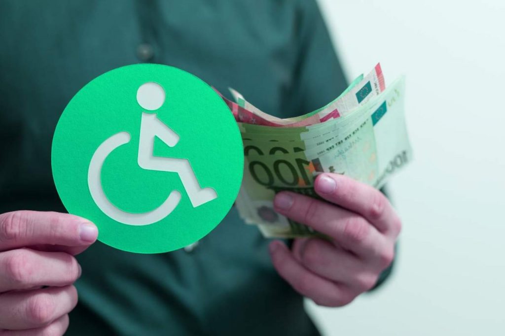 Uomo con in mano un bollino per i disabili e delle banconote euro