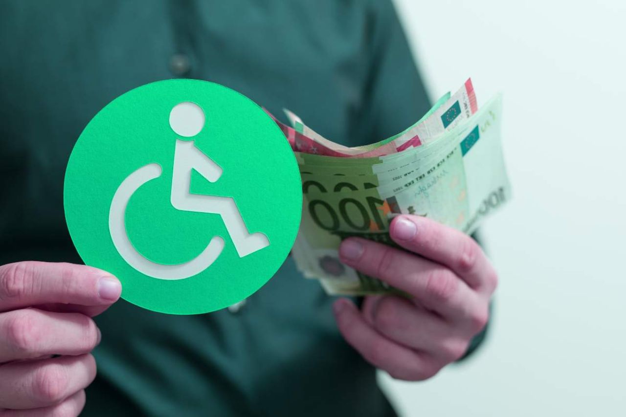 Uomo con in mano un bollino per i disabili e delle banconote euro