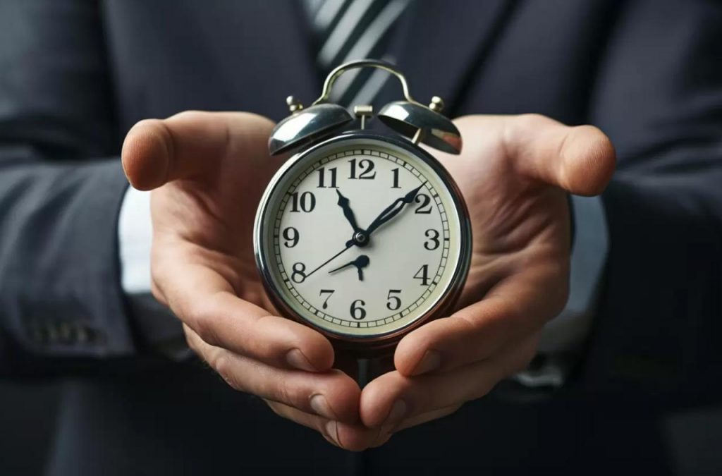lavoratore che tiene in mano una sveglia: concetto del tempo tra le mani