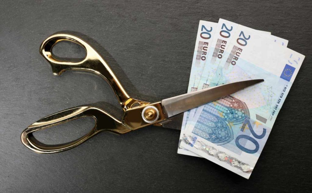 Forbici che tagliano le banconote euro: stipendio dimezzato