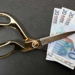 Forbici che tagliano le banconote euro: stipendio dimezzato
