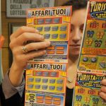 Tabaccaia con pile di gratta e vinci in mano