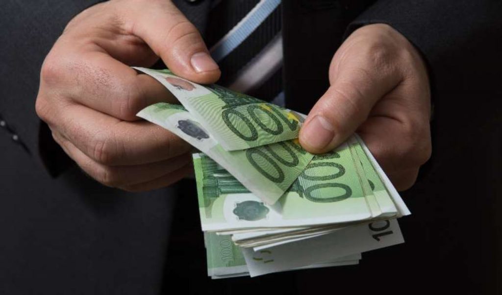 Datore di lavoro che conta una mazzetta di soldi con tagli da 100€, prima di darli al dipendente