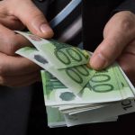 Datore di lavoro che conta una mazzetta di soldi con tagli da 100€, prima di darli al dipendente