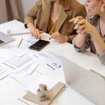 donne che fanno i calcoli alla scrivania con una calcolatrice
