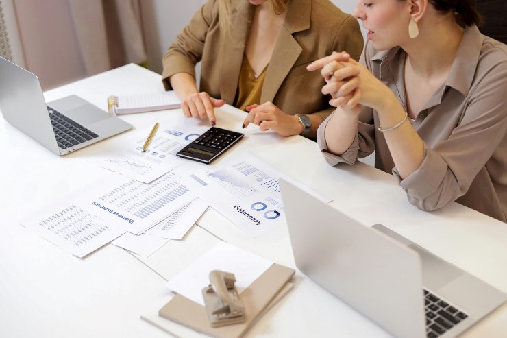donne che fanno i calcoli alla scrivania con una calcolatrice