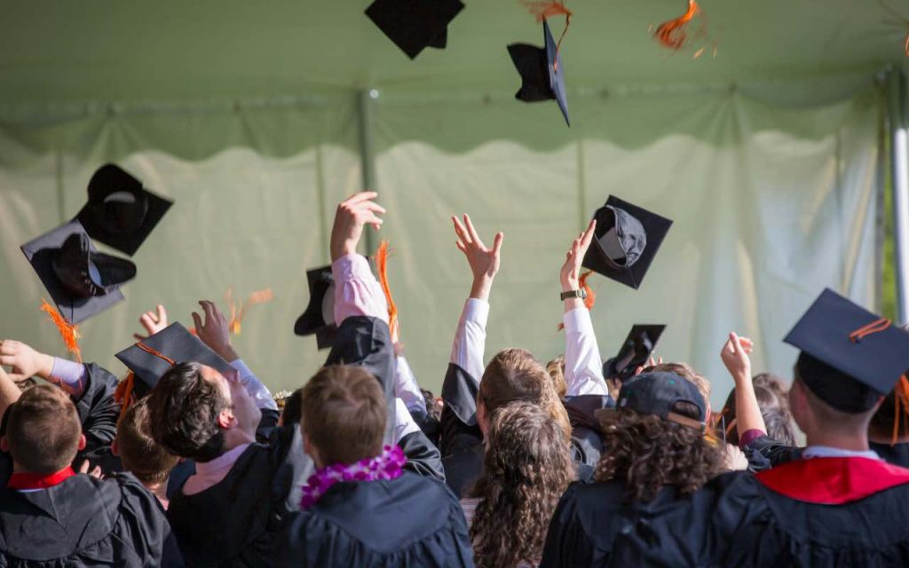 ragazzi che lanciano i capelli del diploma in cielo