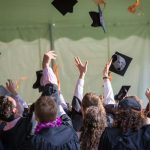 ragazzi che lanciano i capelli del diploma in cielo