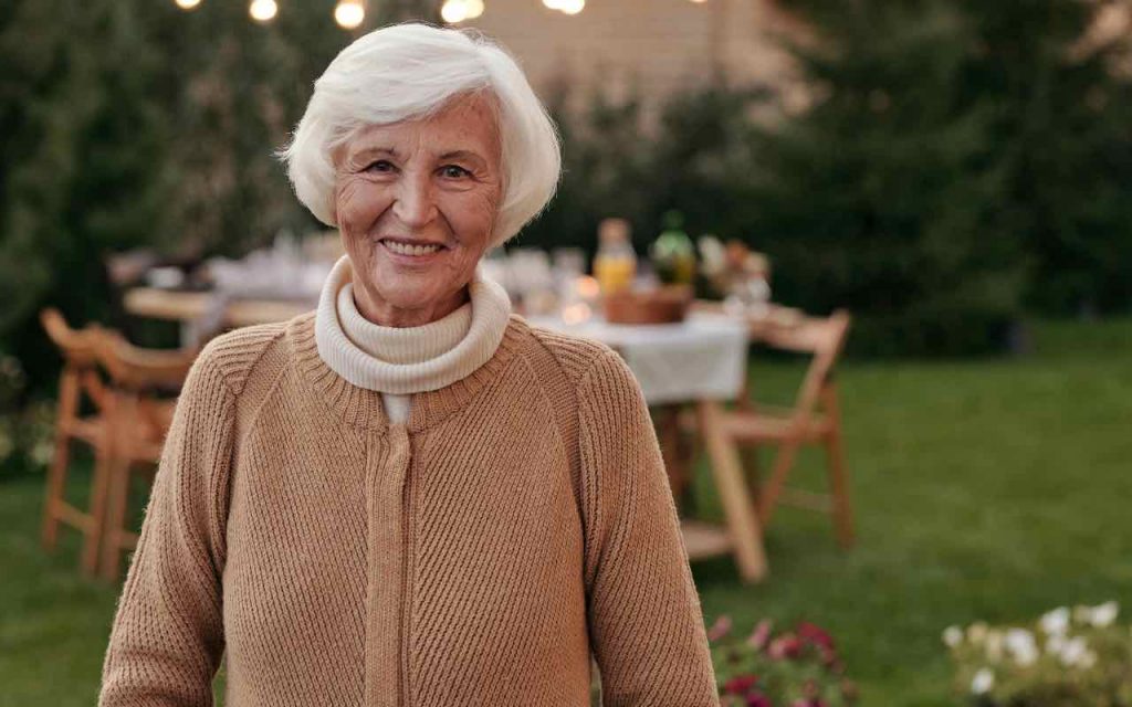donna anziana sorridente in giardino con la tavola imbandita