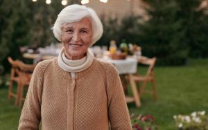 donna anziana sorridente in giardino con la tavola imbandita