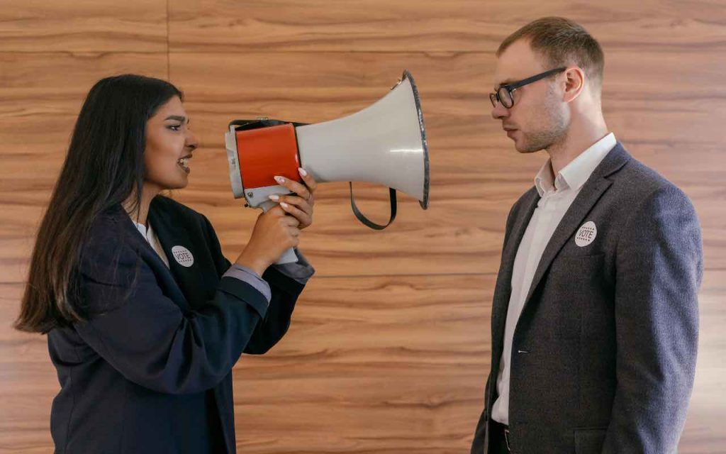 ragazza con megafono che parla a un collega