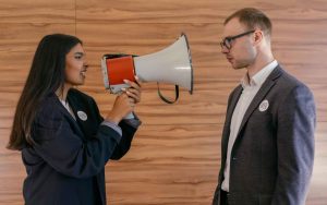 ragazza con megafono che parla a un collega