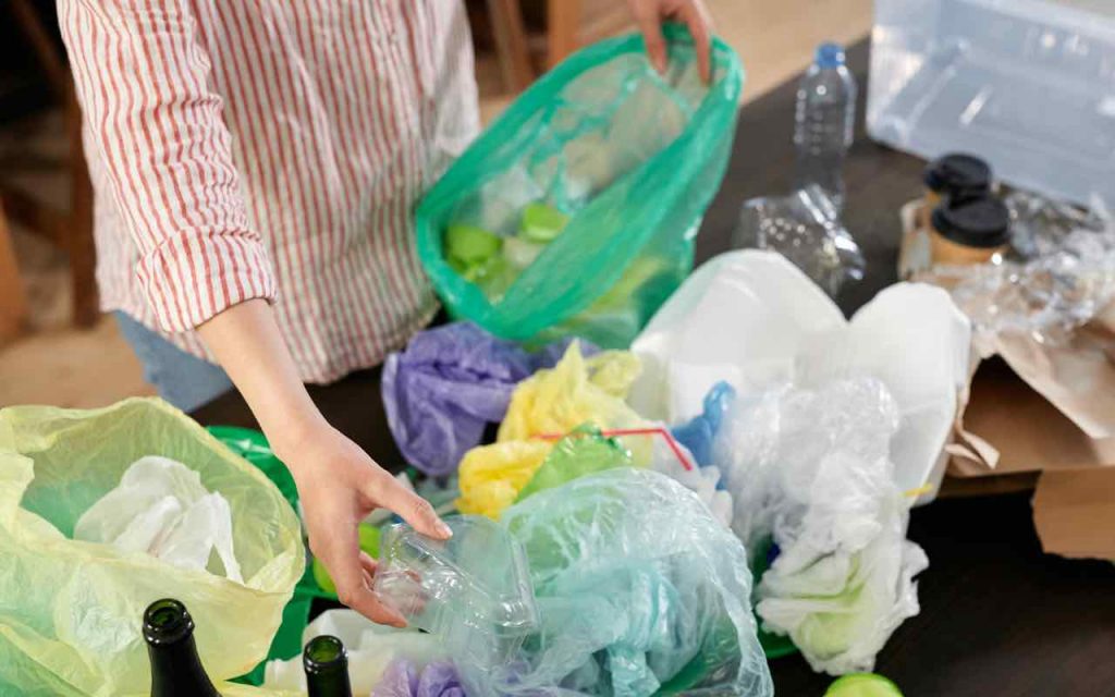 persona che inserisce la plastica di scarto nelle buste
