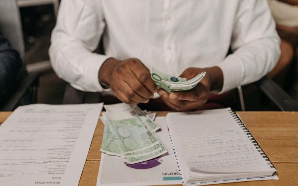uomo che conta le banconote da 100 euro