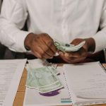 uomo che conta le banconote da 100 euro