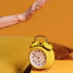 mano che spegne la sveglia sul comodino