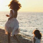 donna che corre con la figlia sulla spiaggia