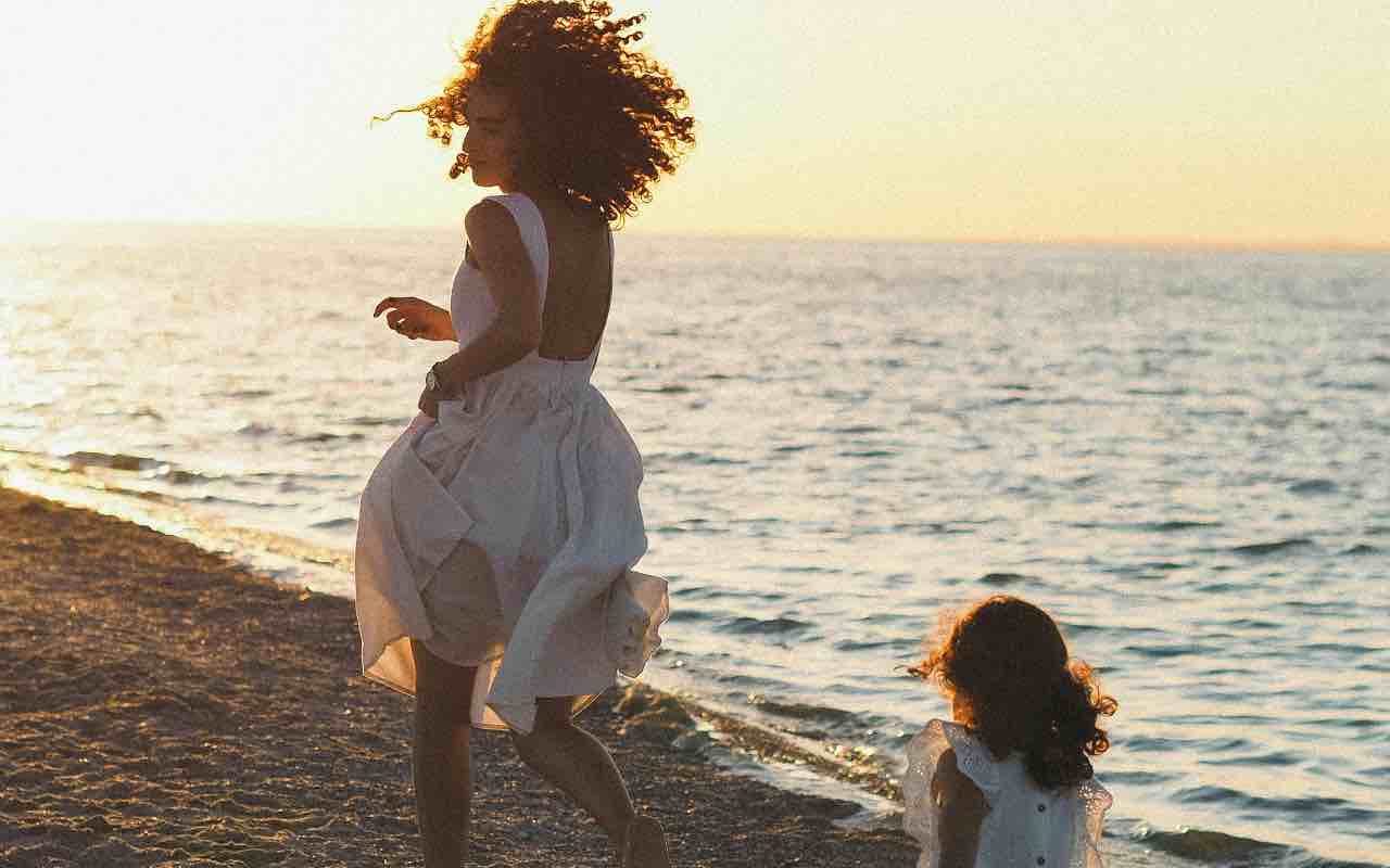 donna che corre con la figlia sulla spiaggia