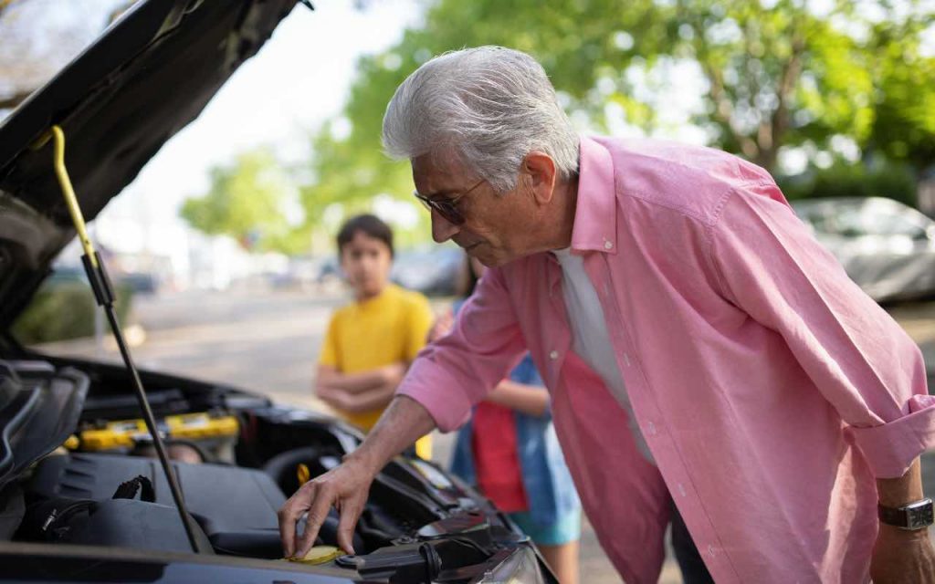 anziano che controlla l'auto