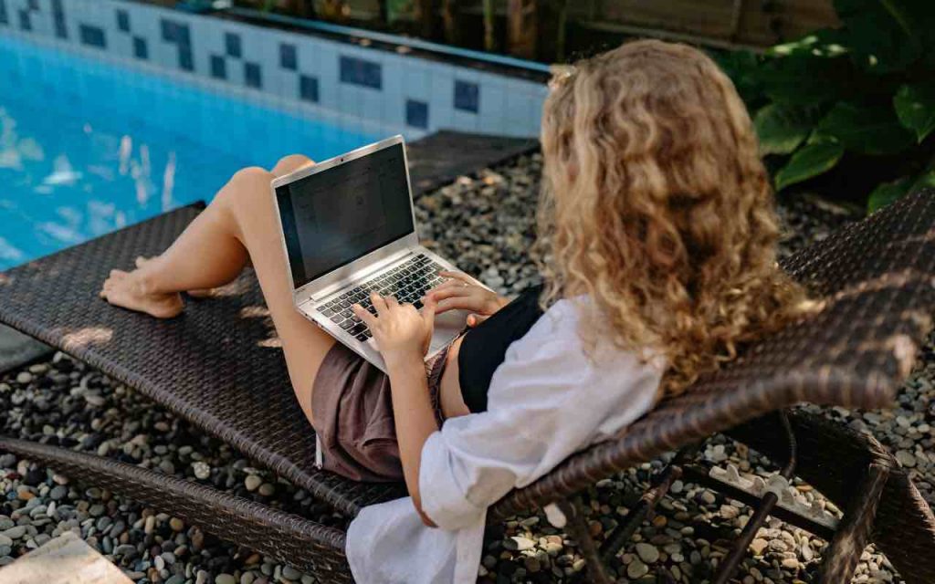 ragazza che lavora al pc a bordo piscina