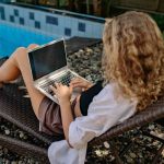 ragazza che lavora al pc a bordo piscina