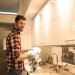ragazzo che pulisce i piatti in cucina