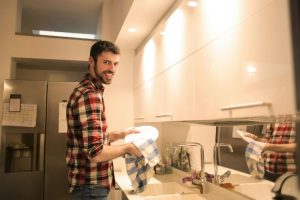 ragazzo che pulisce i piatti in cucina