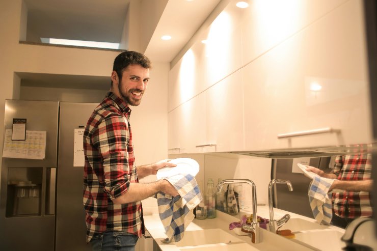 ragazzo che pulisce i piatti in cucina