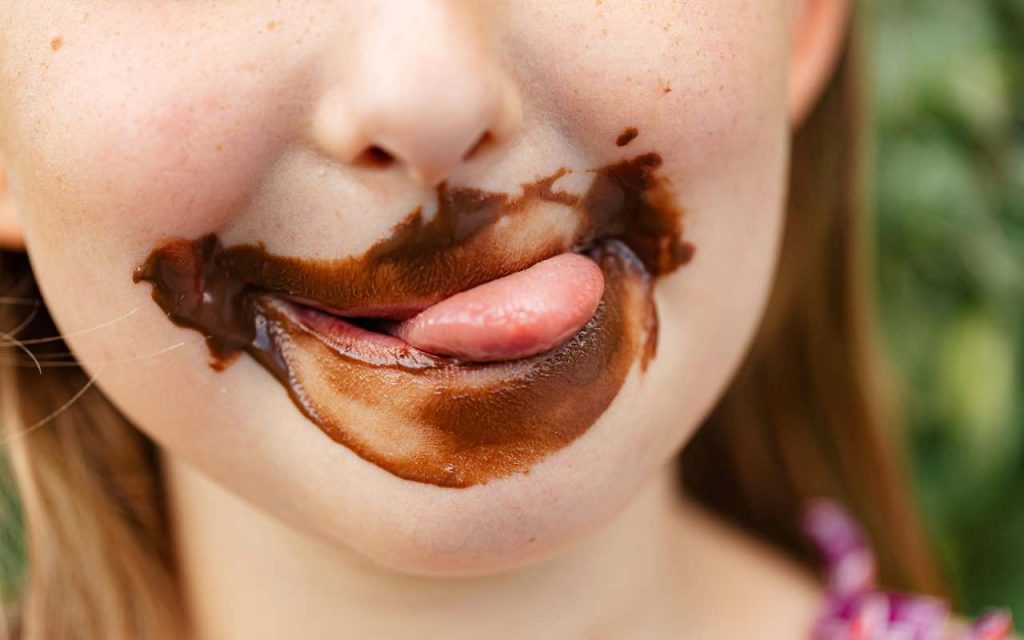 bambina con la bocca sporca di cioccolato