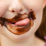 bambina con la bocca sporca di cioccolato